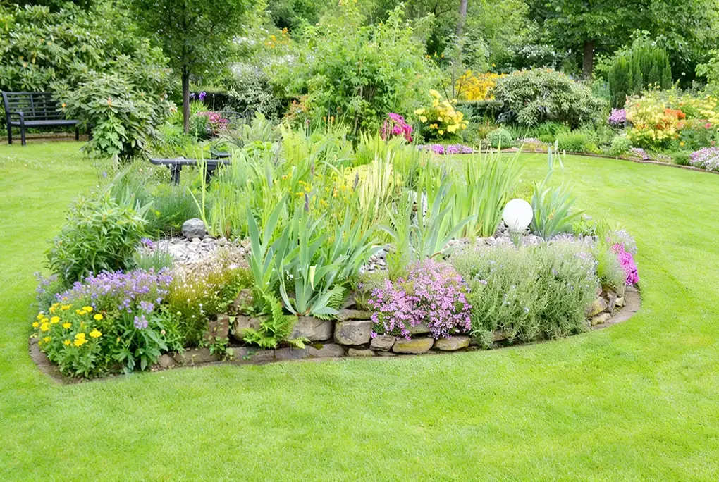 Ovales Steingartenbeet mit Iris und Sommerblumen im Privatgarten – Gartengestaltung Lüneburg Bloomwerk